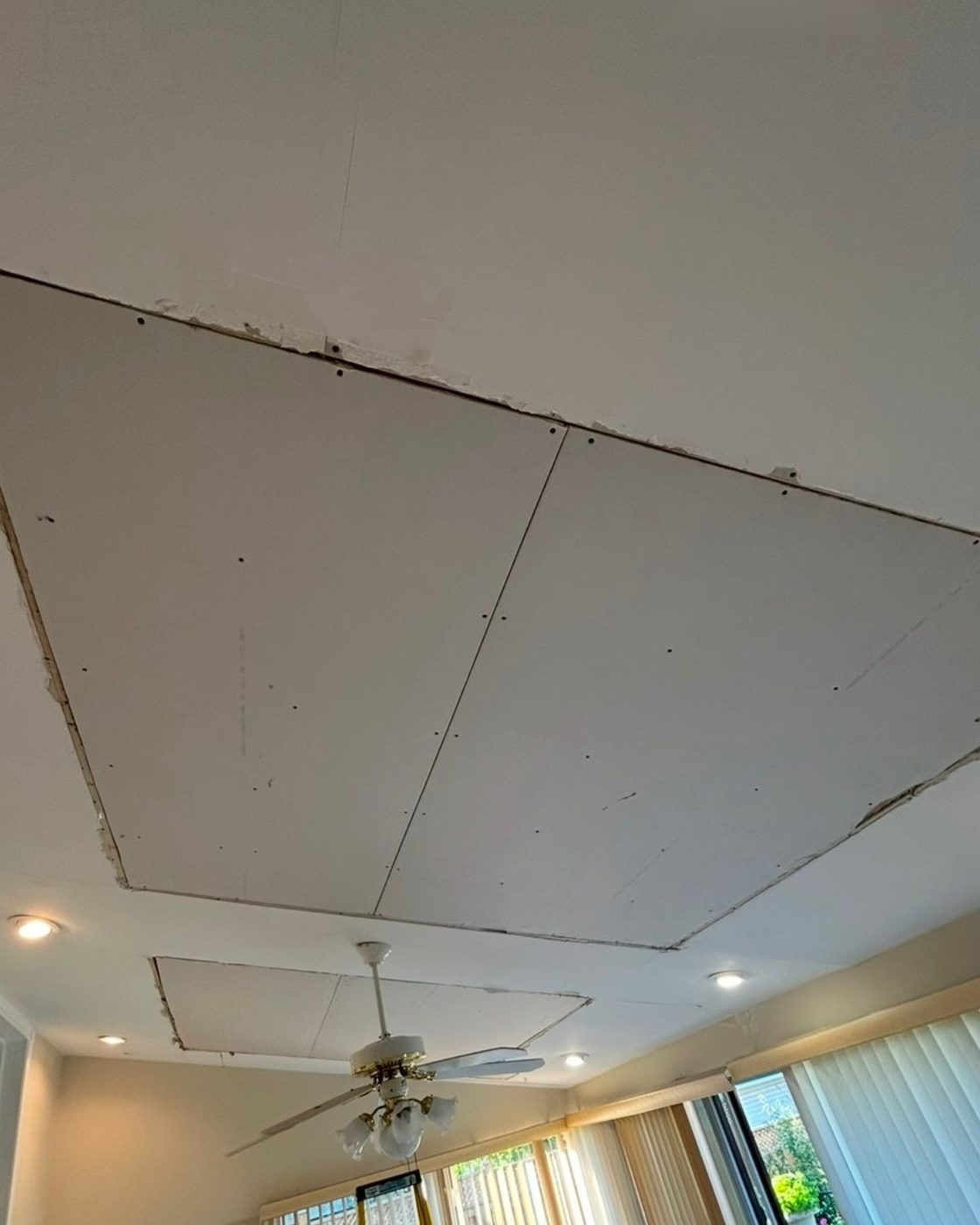 Ceiling before drywall repair, exposed patched panels