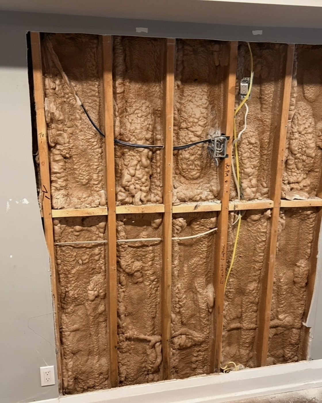 Wall before drywall patch, exposed studs and insulation